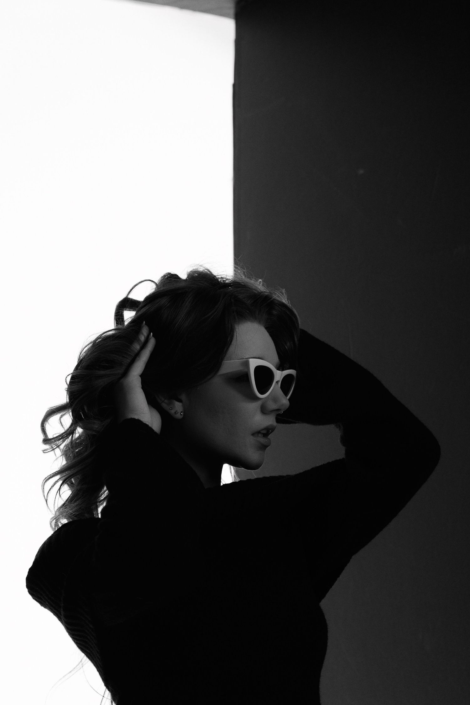 High contrast silhouette of figure with sunglasses in dramatic side lighting.