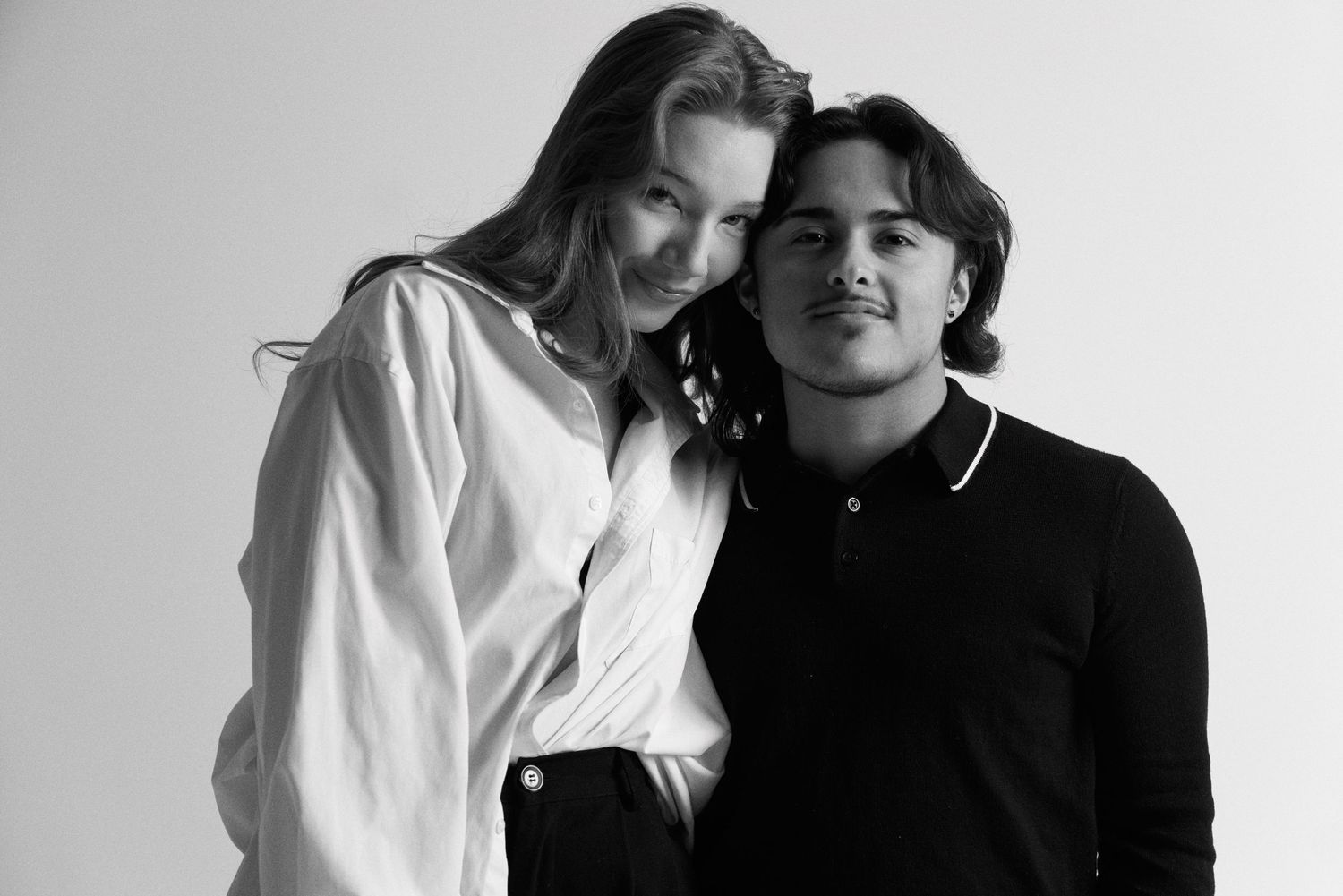 Black and white studio portrait of two people in contrasting black and white outfits.