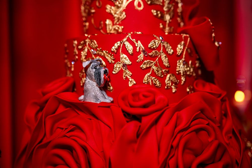 Decorative cake topper detail with metallic embellishments surrounded by red roses.