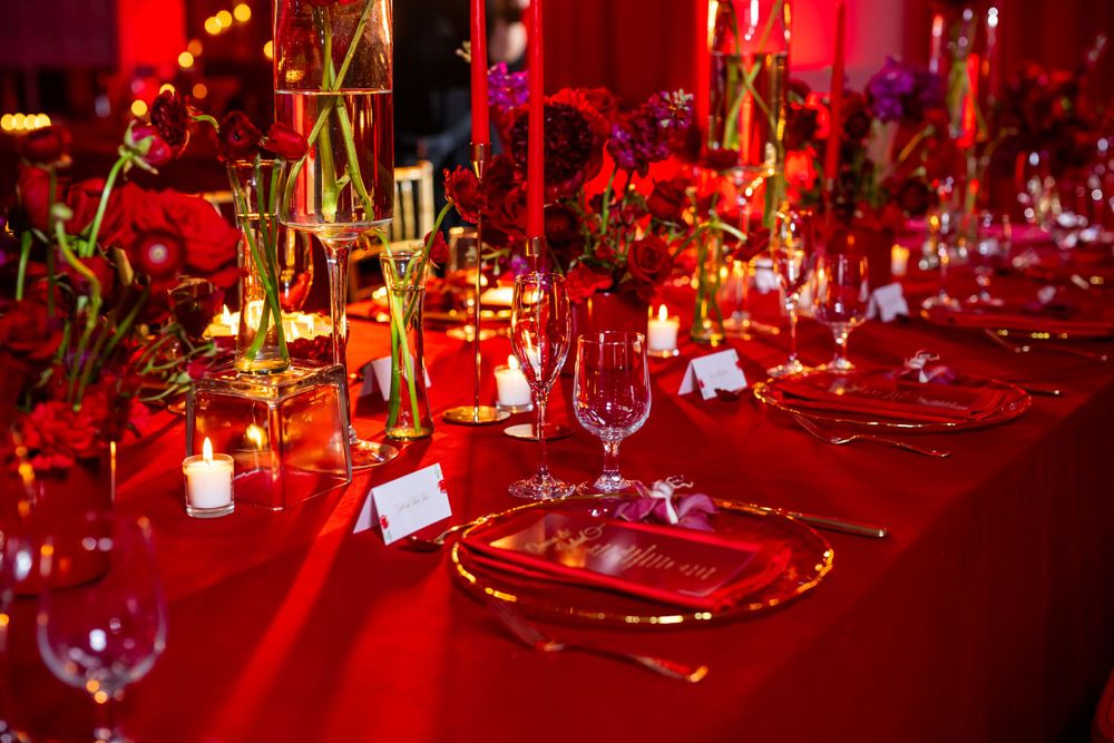 Dramatic red reception table with gold geometric centerpieces and crystal place settings.
