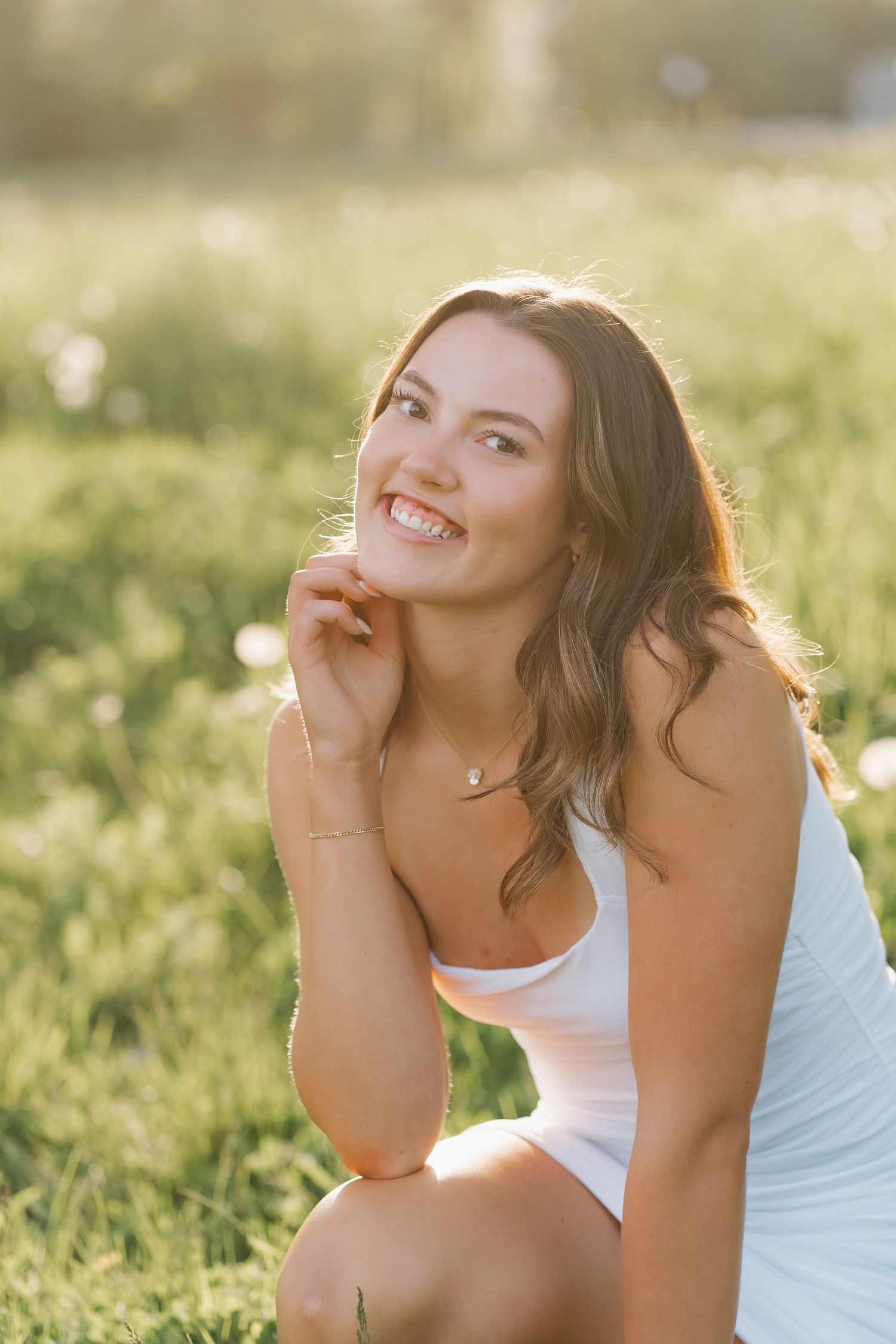 A joyful moment captured in golden sunlight as someone laughs while sitting in a grassy field.