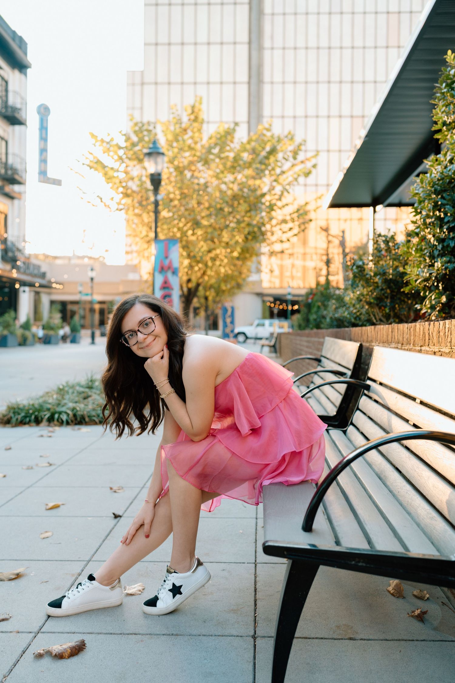 A playful photoshoot on a bench showing dynamic poses in a pink dress against an urban backdrop. Chattanooga Senior Photographer