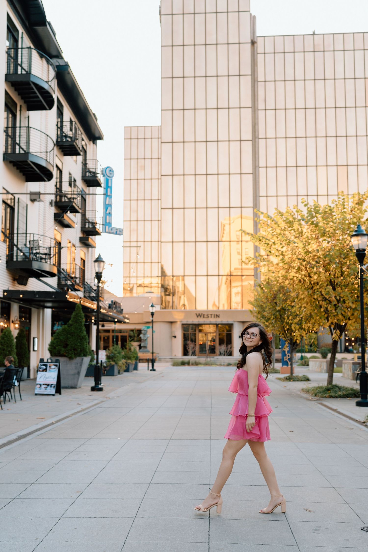 Dancing sequence in a pink dress along a wide urban plaza with modern architecture. Chattanooga Senior Photographer