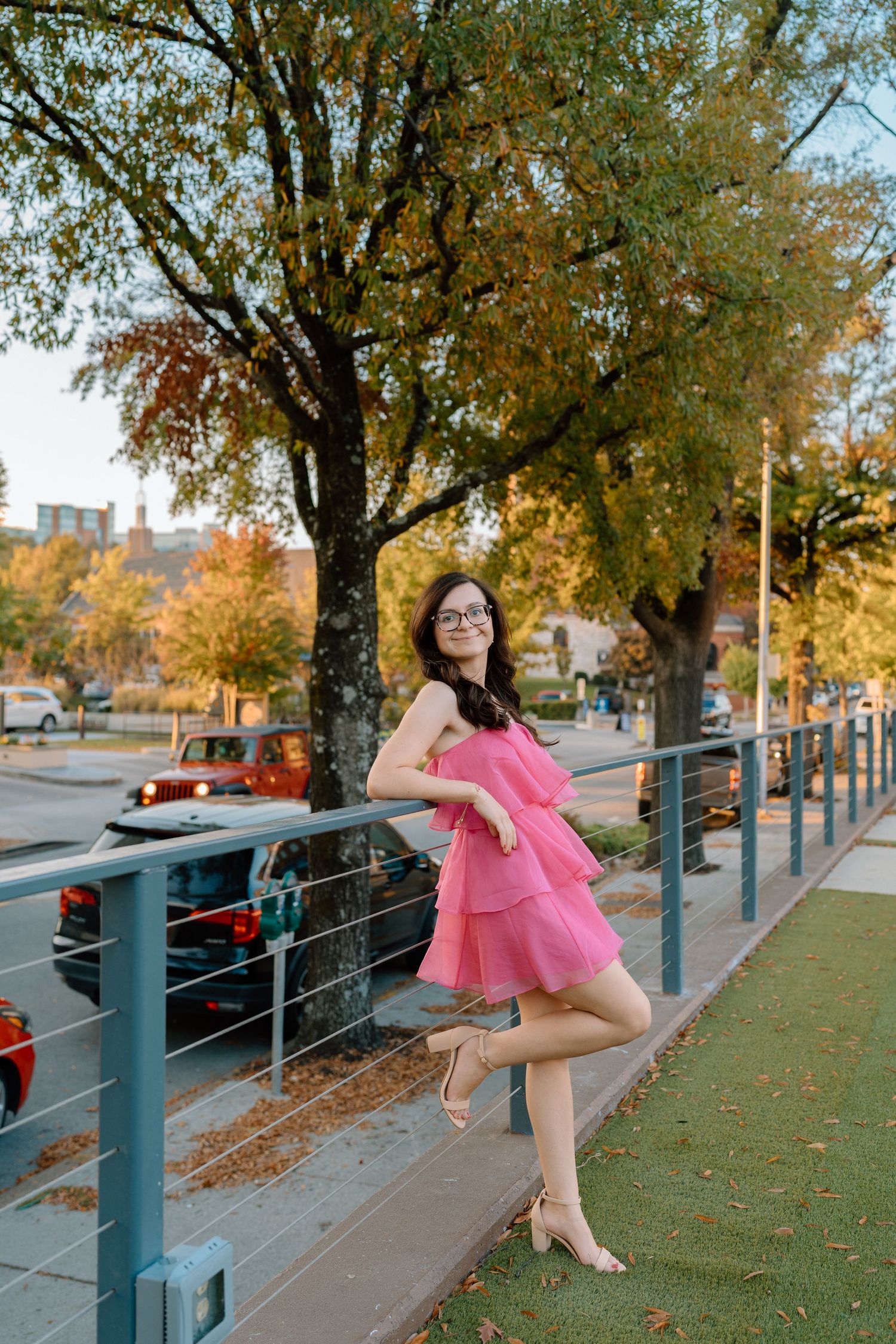 Autumn photoshoot along a railing with fall foliage and urban architecture in the background. Chattanooga Senior Photographer