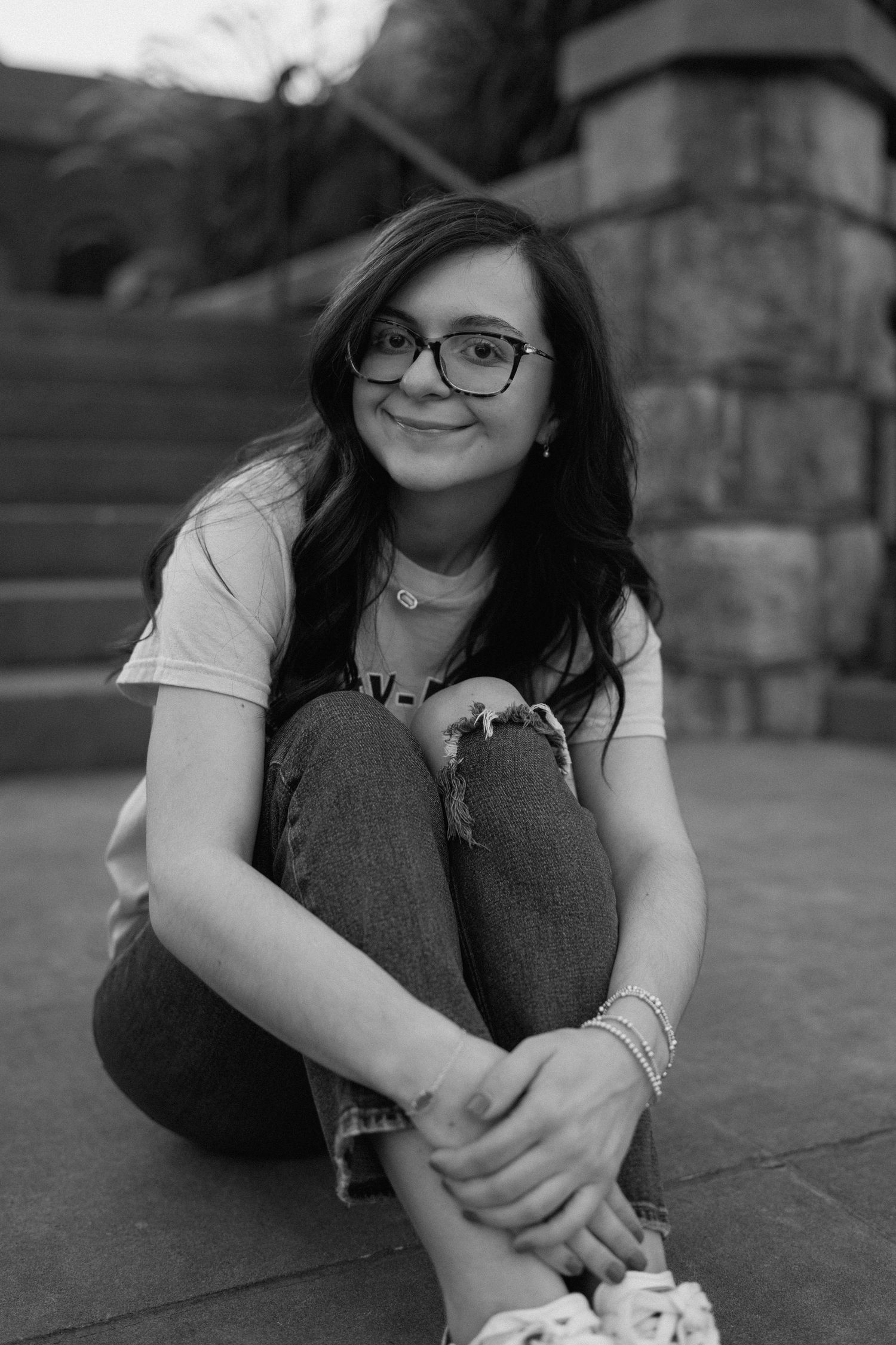 Black and white portrait series showing a person lying down in casual attire with glasses. Chattanooga Senior Photographer
