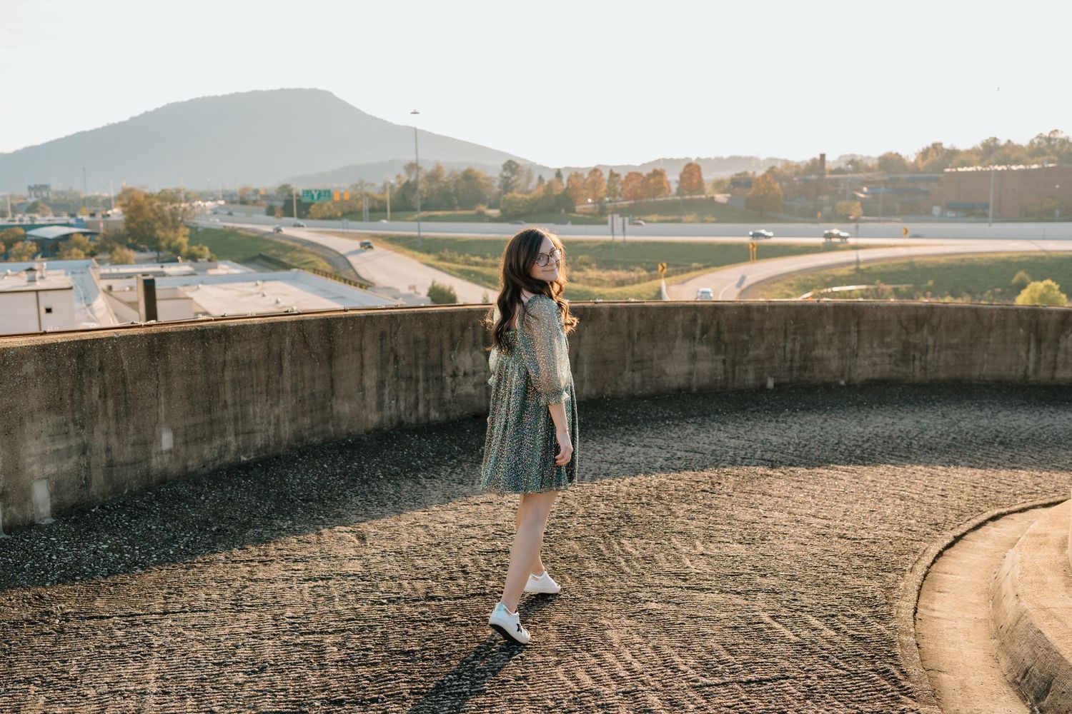 Person in dress walking along curved concrete wall with mountain landscape in background. Chattanooga Senior Photographer