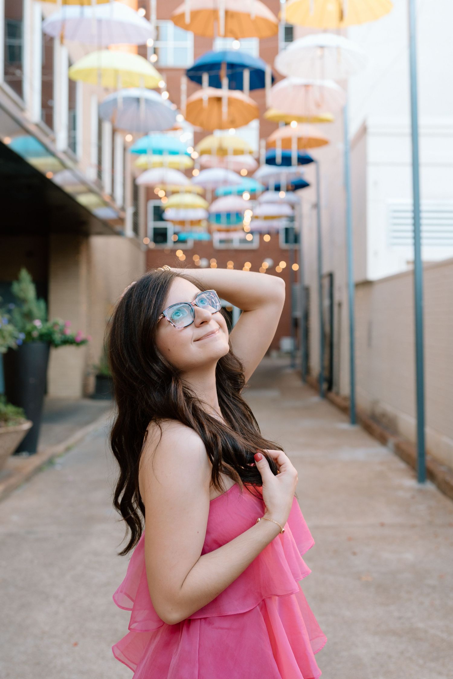 Person in pink summer dress poses beneath decorative suspended umbrellas. Chattanooga Senior Photographer