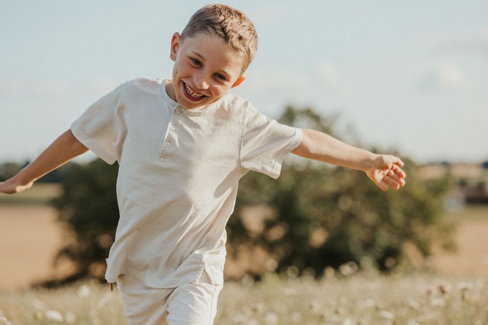A child in a white shirt runs and plays joyfully in a golden wheat field at sunset.