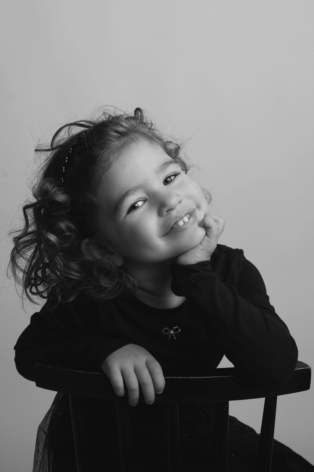 A series of black and white photos showing a child in a dark sweater posing playfully against a light background.