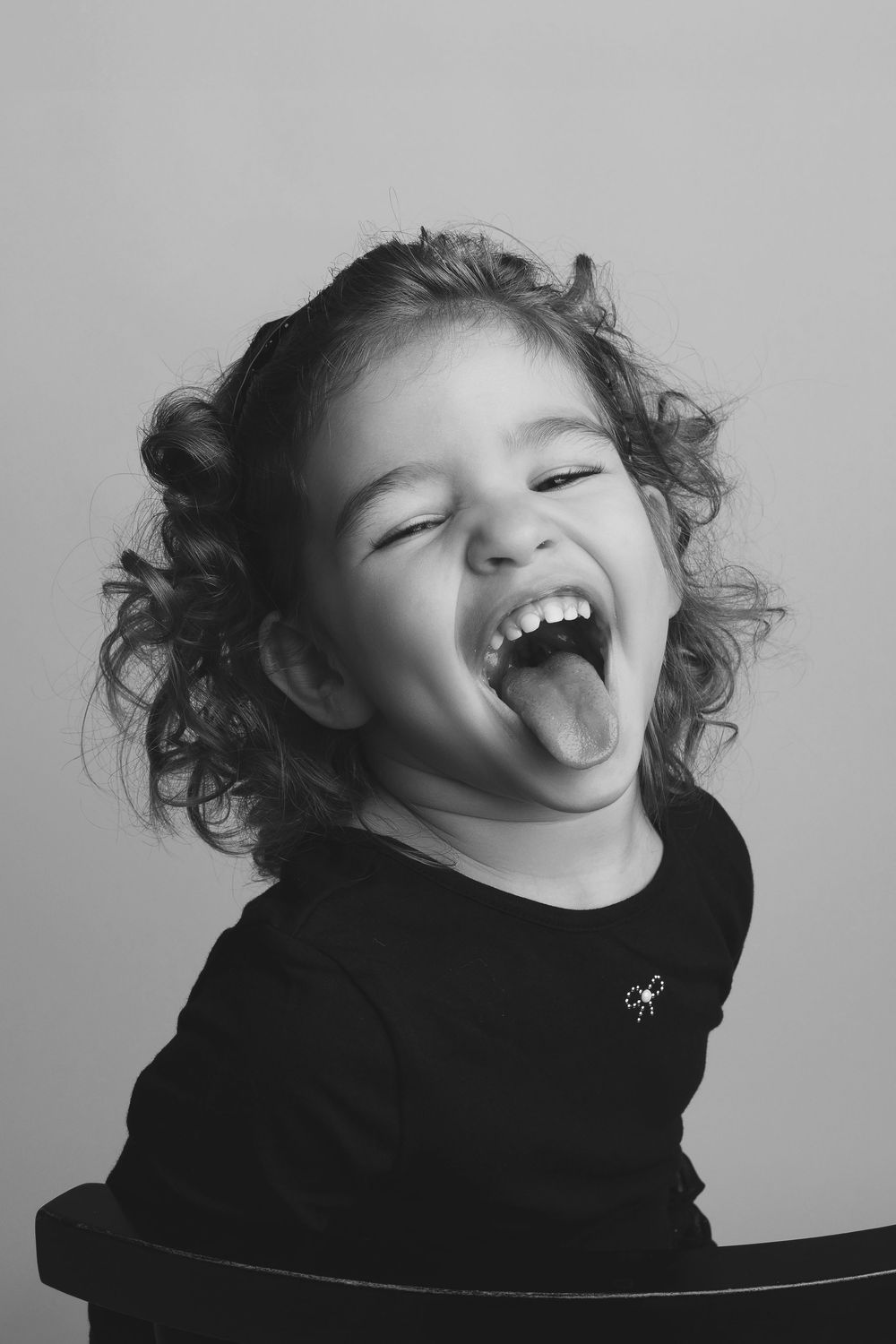Black and white portrait series showing joyful expressions and playful laughter against a simple background.