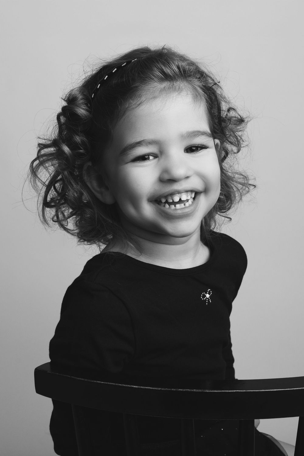 Black and white portrait series showing joyful expressions and curly hair against a simple studio background.