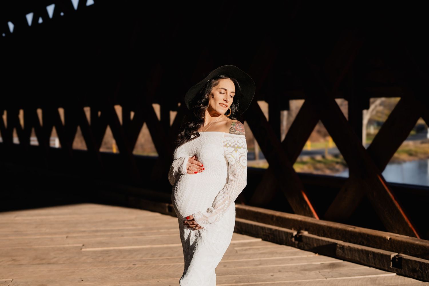 Sunlit portrait on wooden bridge with off-shoulder lace wedding gown and soft natural lighting.
