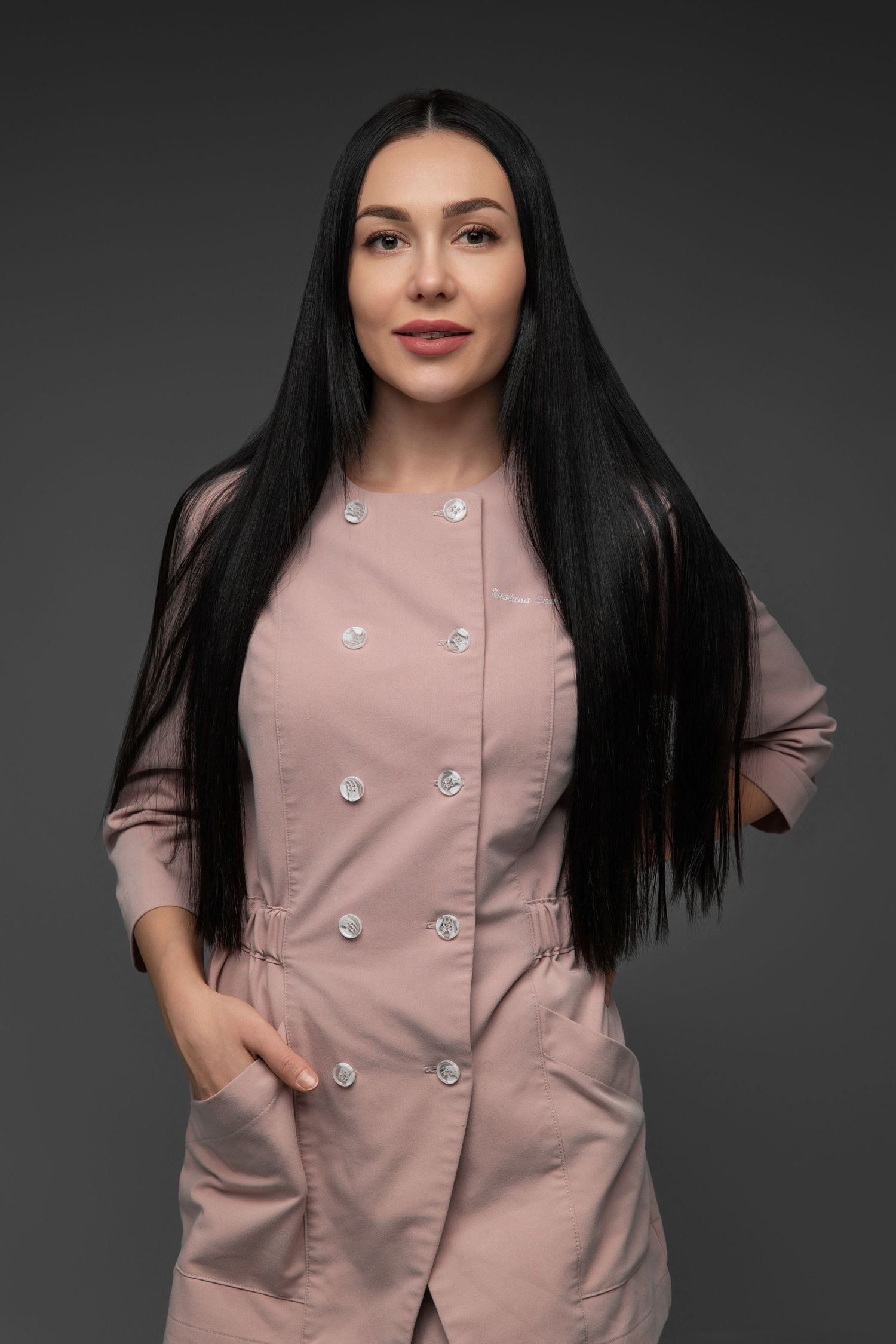 Professional retro-style medical uniform in dusty pink with silver buttons on gray studio background.