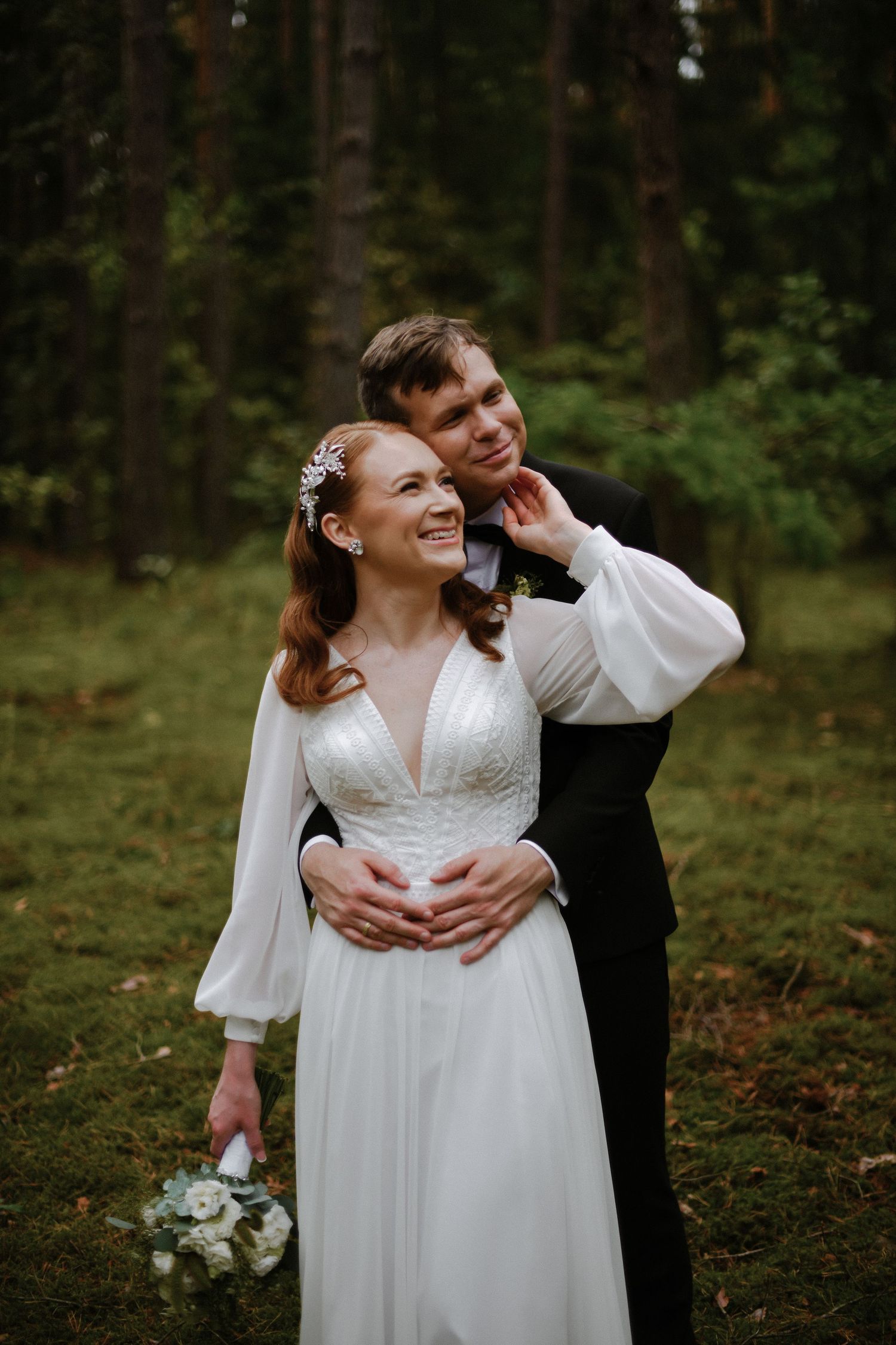 A wedding party walking outdoors in formal attire on a tree-lined path.
