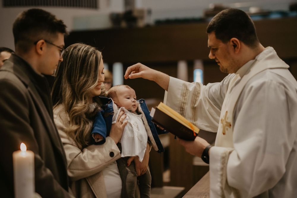 A baptismal ceremony being performed in a church with lit candles.