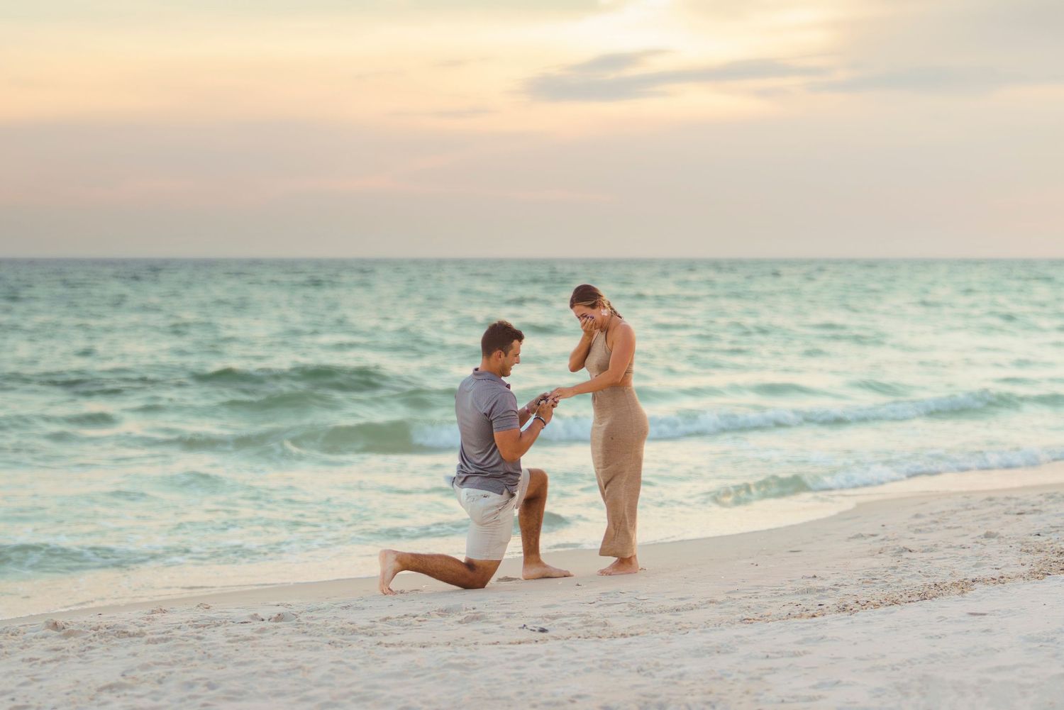 A romantic beach proposal at sunset with turquoise waters and white sand creating a dreamy coastal backdrop.