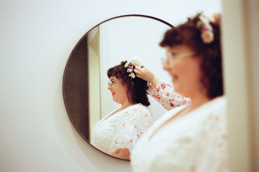 A vintage-style floral wedding scene reflected in a circular mirror shows delicate lace and cherry blossoms.