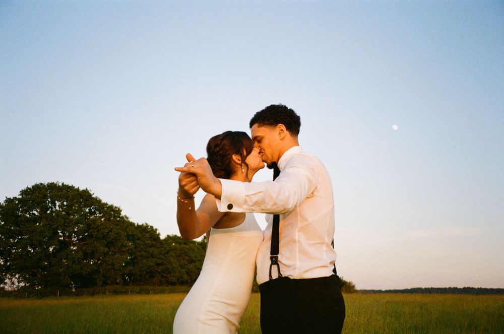 Romantic dance between newlyweds in a golden sunset field.  Shot on 35mm film.