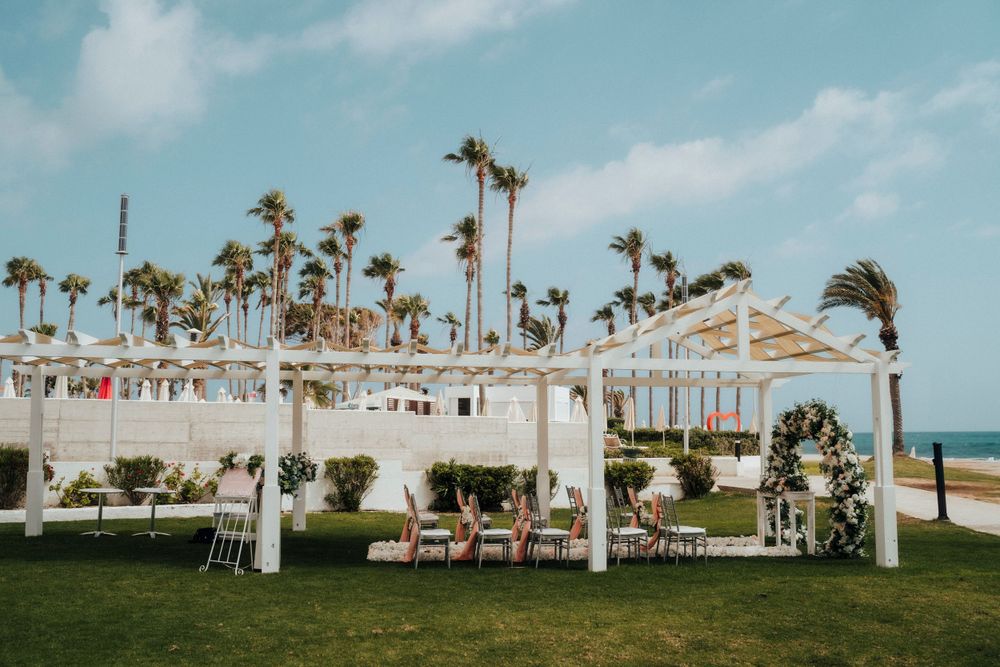 A beachside wedding setup with white canopy and palm trees swaying in the breeze at a tropical venue.