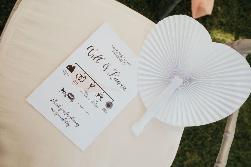 Wedding timeline schedule card displayed with a white paper fan on an open book.