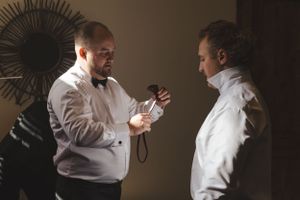 Two men in formal attire having a conversation in a dimly lit room.