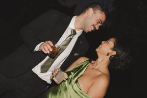 A couple in formal attire share a romantic dance moment at an evening celebration.
