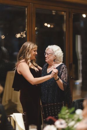 Two women share an intimate dance moment at an evening wedding reception.