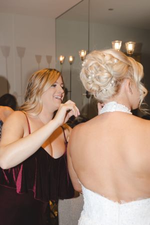 Wedding dress preparations in a bridal suite with elegant lighting and mirrors.