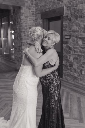 Emotional embrace captured in black and white at wedding venue with stone walls.