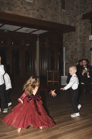 Dancing together at a reception, with a child dancing energetically in front of someone wearing a flowing red dress.