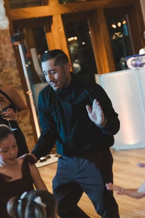 Reception guest dancing energetically on wooden floor at evening wedding celebration.