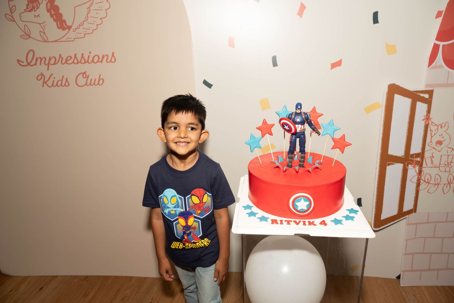 Birthday celebration setup with superhero-themed cake at Impressions Kids Club.