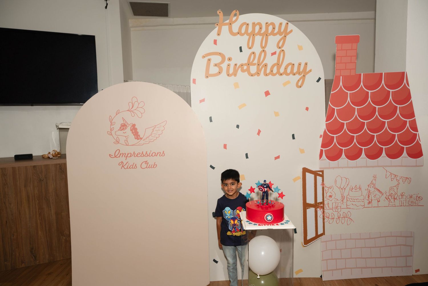 Child posing in front of Happy Birthday wall decoration at Impressions Kids Club.
