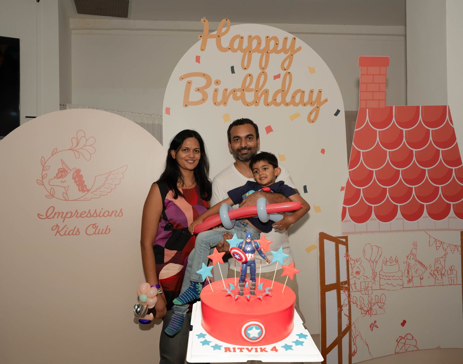 Family portrait in front of birthday decorations at Impressions Kids Club.