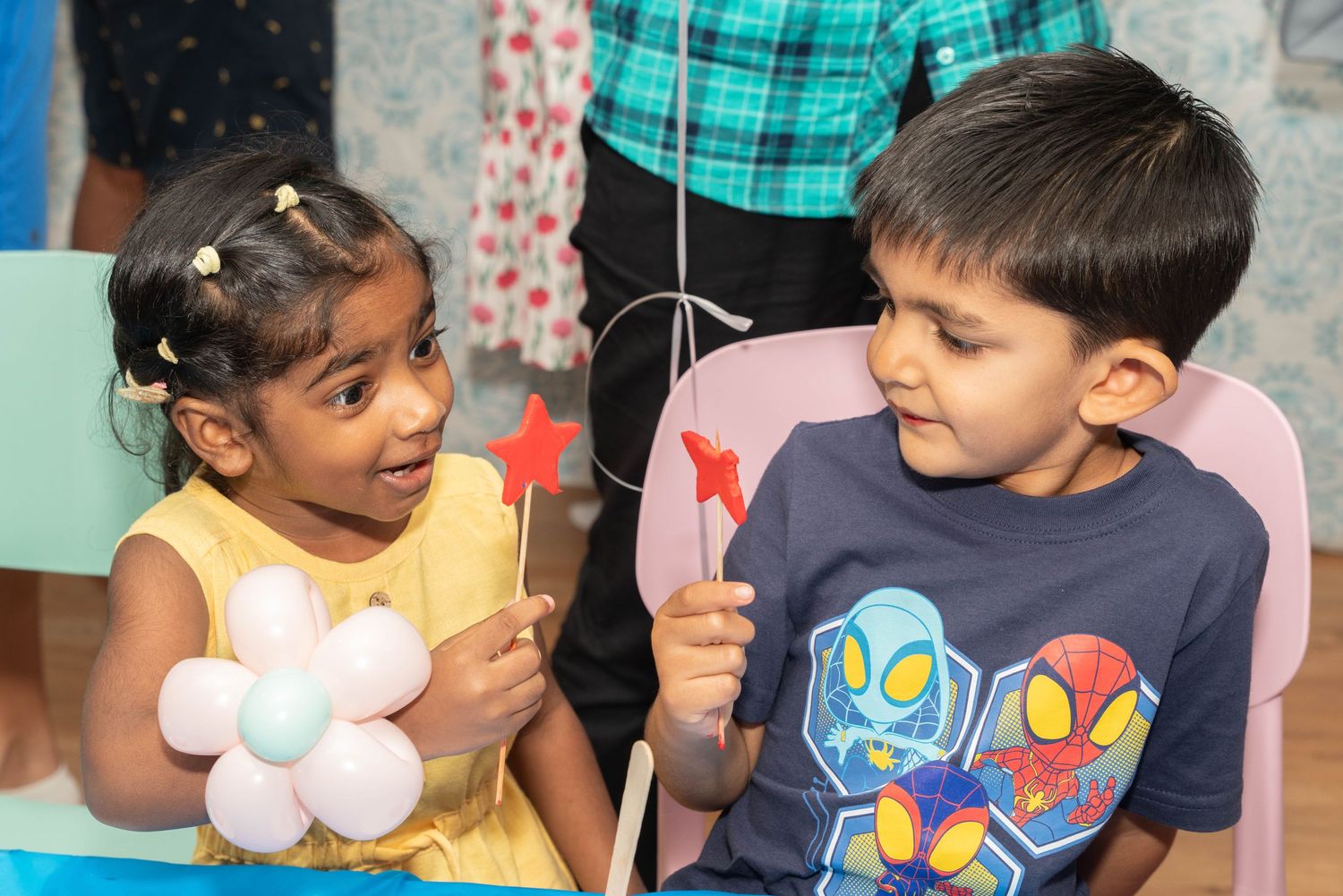 Two children enjoy party activities while seated at tables with festive decorations.