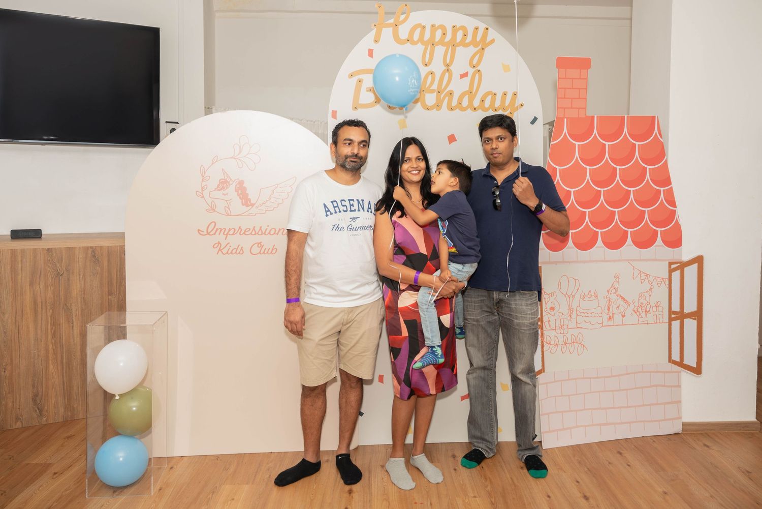 Birthday party scene with balloon decorations and geometric wall design.