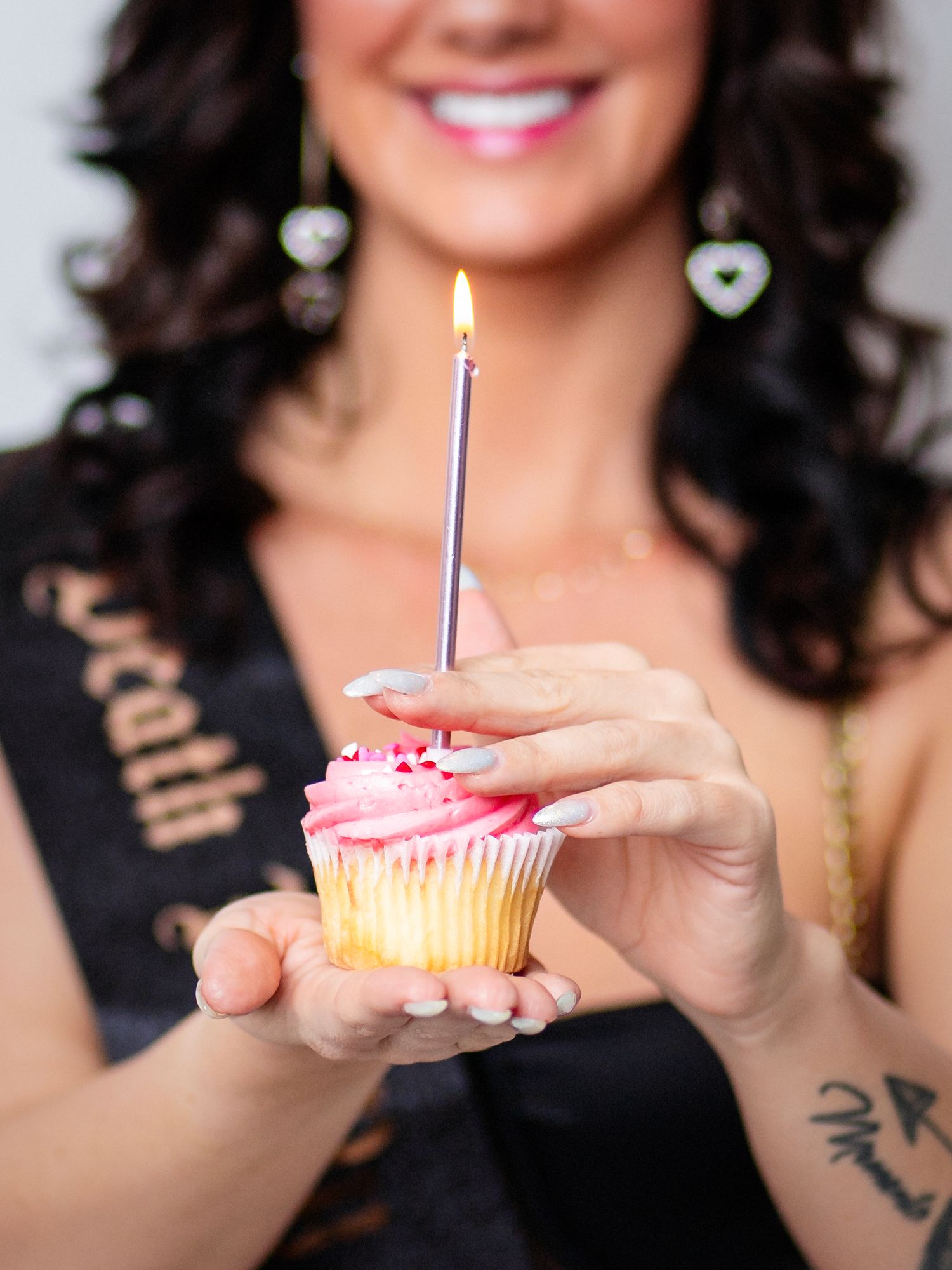 Photo of a beautiful woman holding a cupcake with pink icing and a candle for her birthday photo session. Taking in Dandridge TN studio