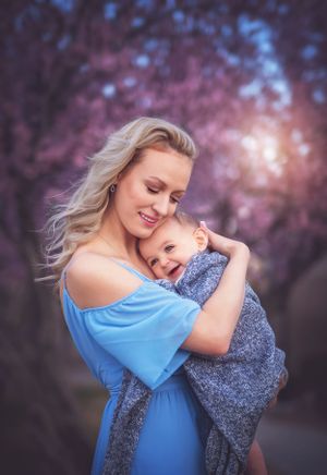A tender moment captured between parent and child against blurred pink cherry blossoms in springtime.