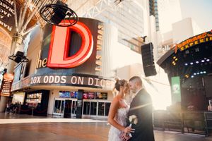 A couple shares a romantic moment in front of the iconic D casino sign in downtown Las Vegas at sunset.
