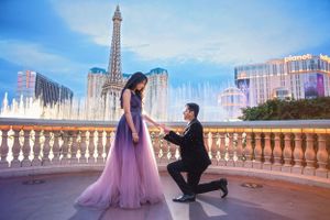 A proposal moment in front of the Bellagio fountains in Las Vegas with the Eiffel Tower and casinos in background.