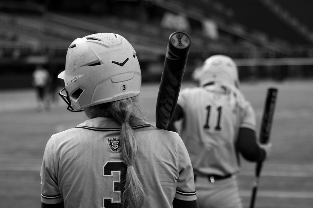 Black and white image of baseball players with helmets and bats on a field.