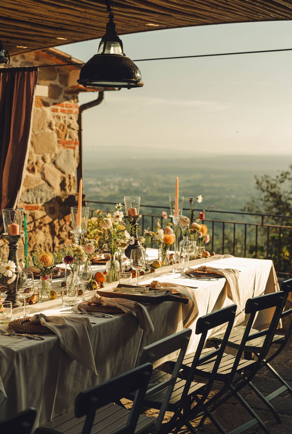 Elegant wedding table setting on a terrace overlooking a scenic countryside vista.