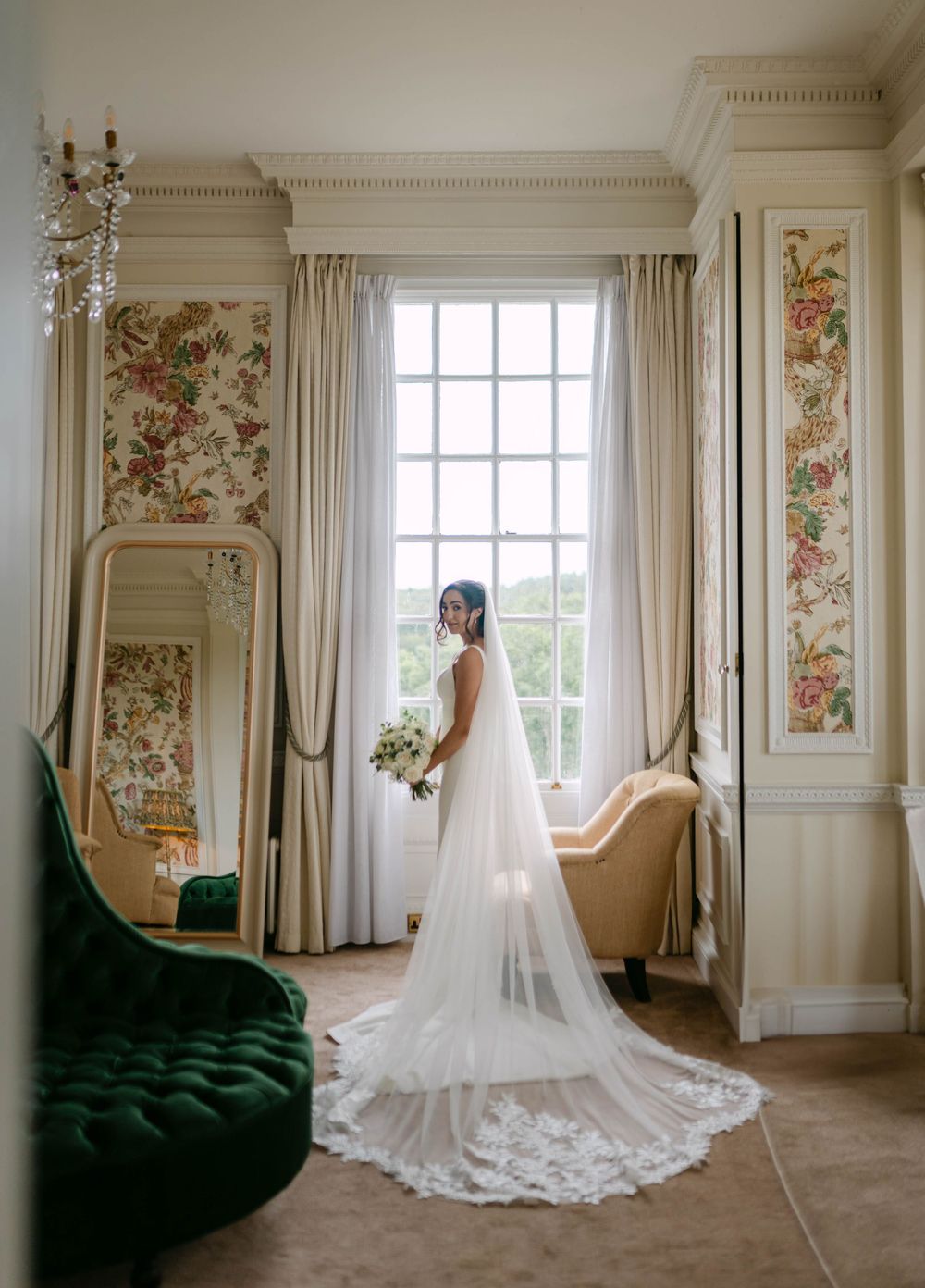 Bridal portraits in an elegant room with floral wallpaper and flowing white curtains.