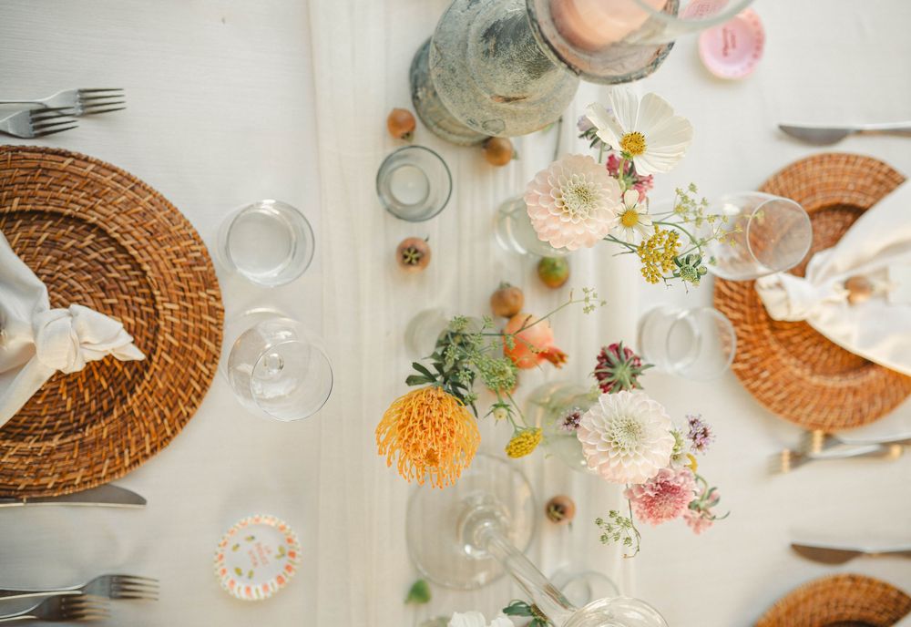 Overhead view of a beautifully decorated wedding table with woven placemats and colorful floral arrangements.