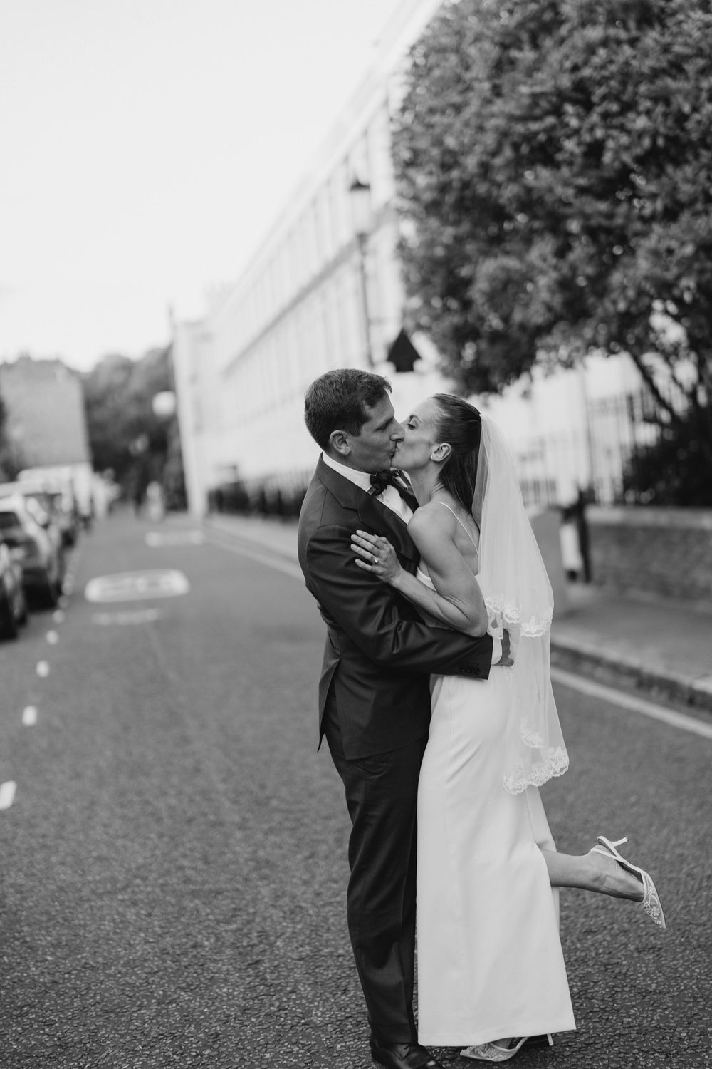 Black and white wedding photos showing romantic moments between newlyweds on a tree-lined path.