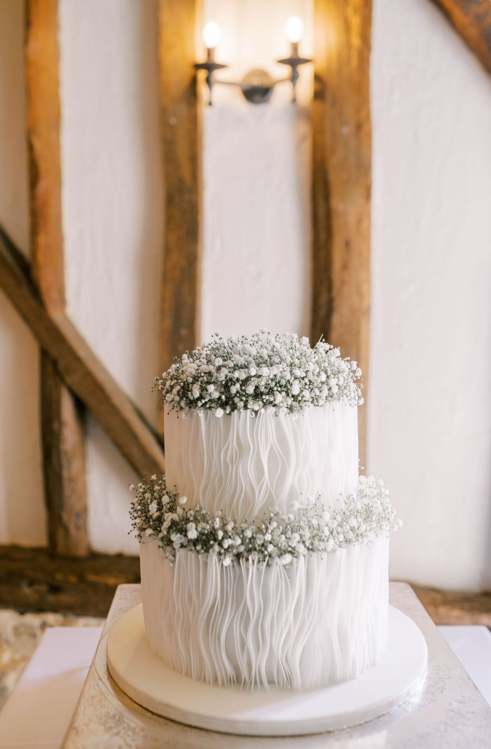 Elegant white wedding cake decorated with delicate ruffles and baby's breath flowers.