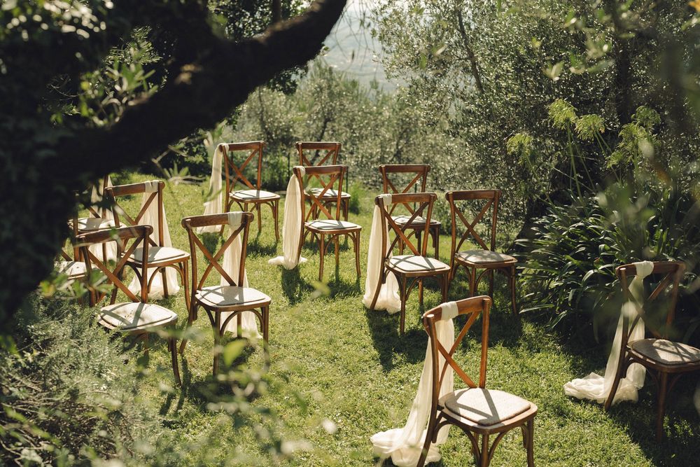 Rustic wooden chairs arranged in rows for an outdoor garden wedding ceremony.