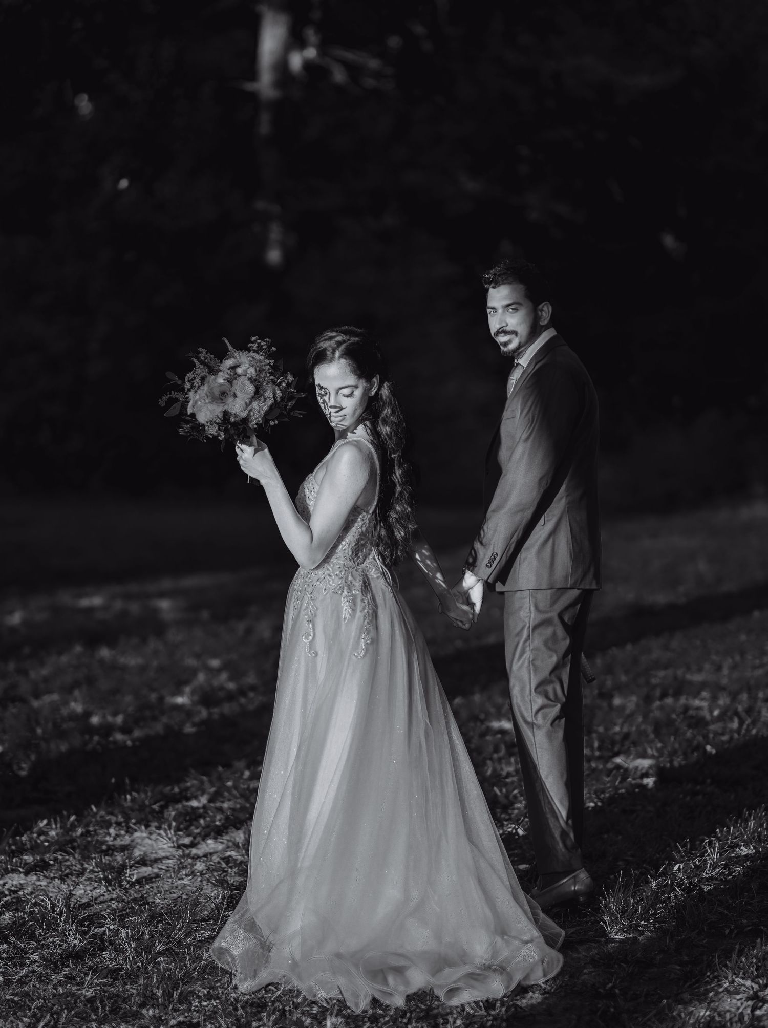 A couple dances together in a romantic black and white photo outdoors.