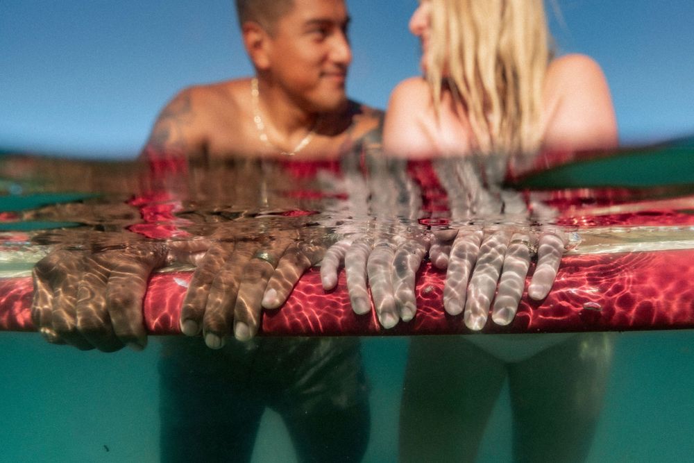 A couple shares a romantic moment floating together in the calm waters of the Destin Jetties, Florida.