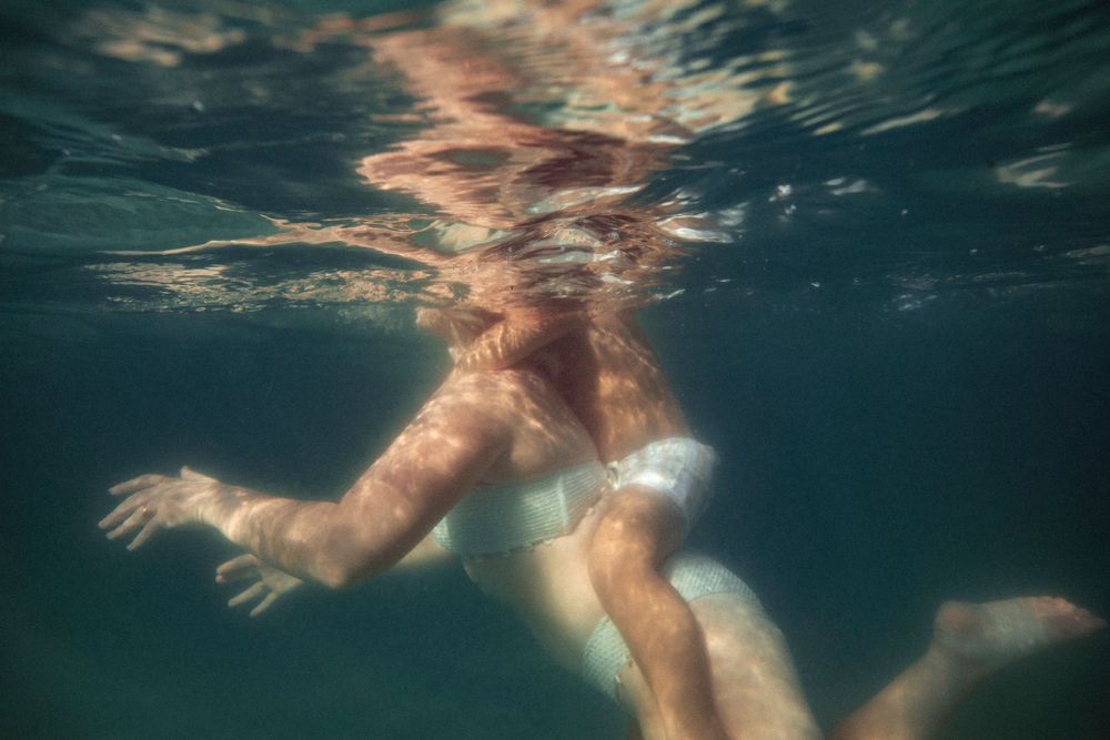 A joyful family enjoying an underwater photoshoot at the Destin Jetties, surrounded by clear emerald water and bright skies.